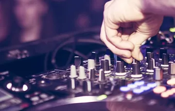 Un équipement de DJ avec une main en train d’ajuster les commandes