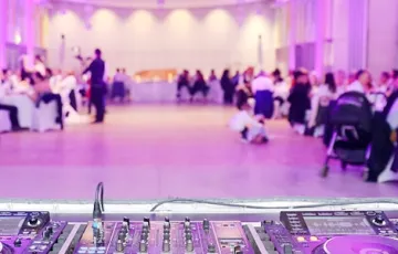 Une vue large d’une piste de danse avec un éclairage violet et des personnes assises
